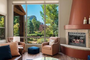 Una sala de estar con chimenea, ventanas amplias y vistas a un paisaje montañoso.
