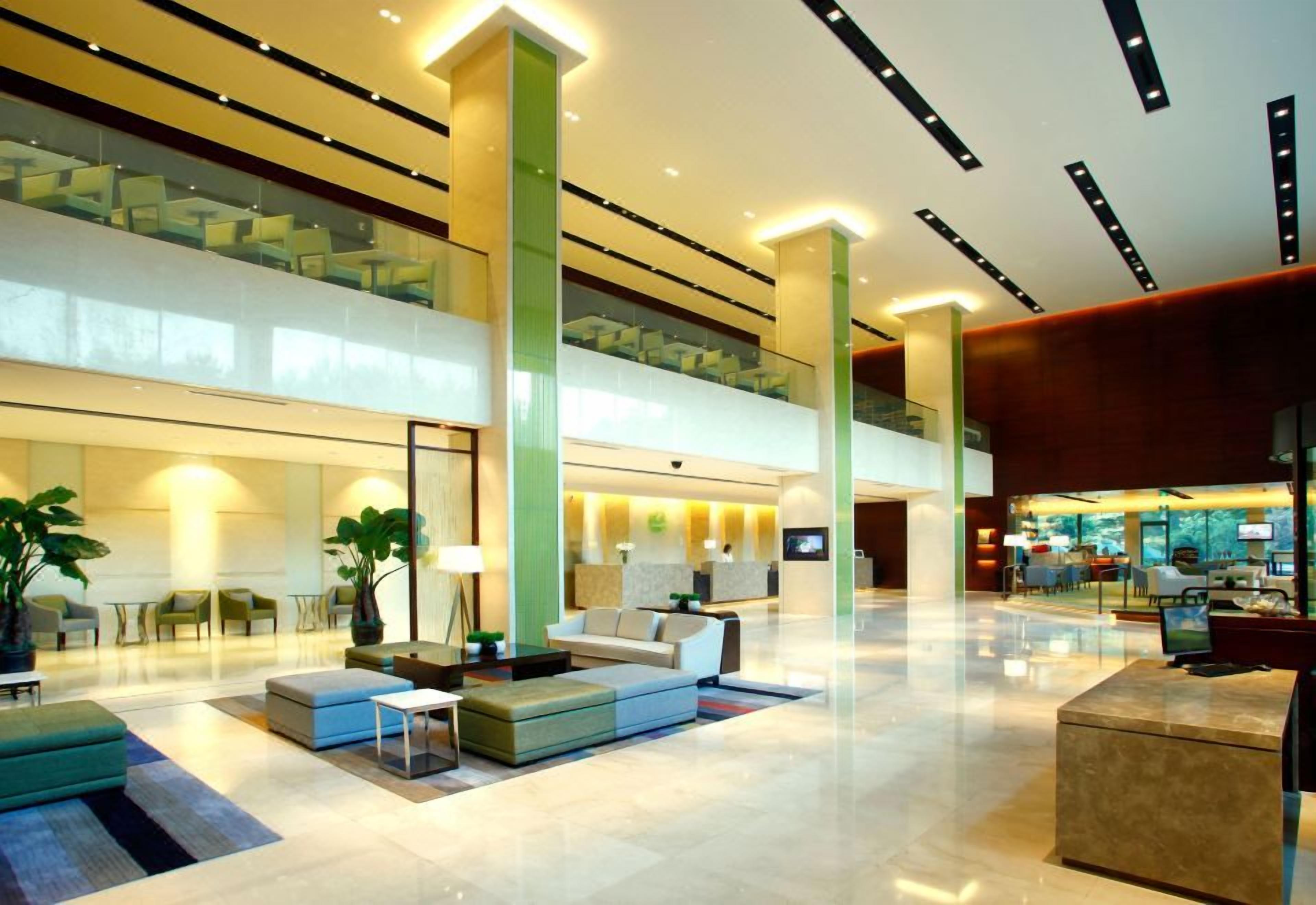 A spacious lobby with a seating area, a reception desk, and a staircase leading to an upper level.