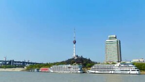 A river with two cruise ships docked, a tall tower, and a modern building. - Holiday Inn WUHAN RIVERSIDE by IHG (Wuhan)
