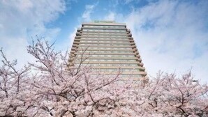 A multi-story building with a modern architectural design, surrounded by cherry blossom trees. - Holiday Inn WUHAN RIVERSIDE by IHG (Wuhan)