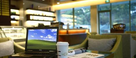 A laptop on a table with a coffee cup and a menu.