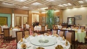 A banquet hall with round tables, chairs, and a central decorative element. - Holiday Inn WUHAN RIVERSIDE by IHG (Wuhan)