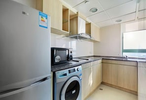 Une cuisine compacte équipée d’un réfrigérateur, d’un four à micro-ondes et d’un lave-linge.