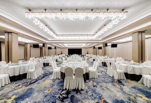 A large banquet hall with round tables, white chairs, and a blue carpet. - Holiday Inn WUHAN RIVERSIDE by IHG (Wuhan)