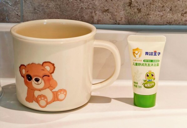 Una taza de cerámica con diseño de oso y un tubo de crema con ilustración de rana.