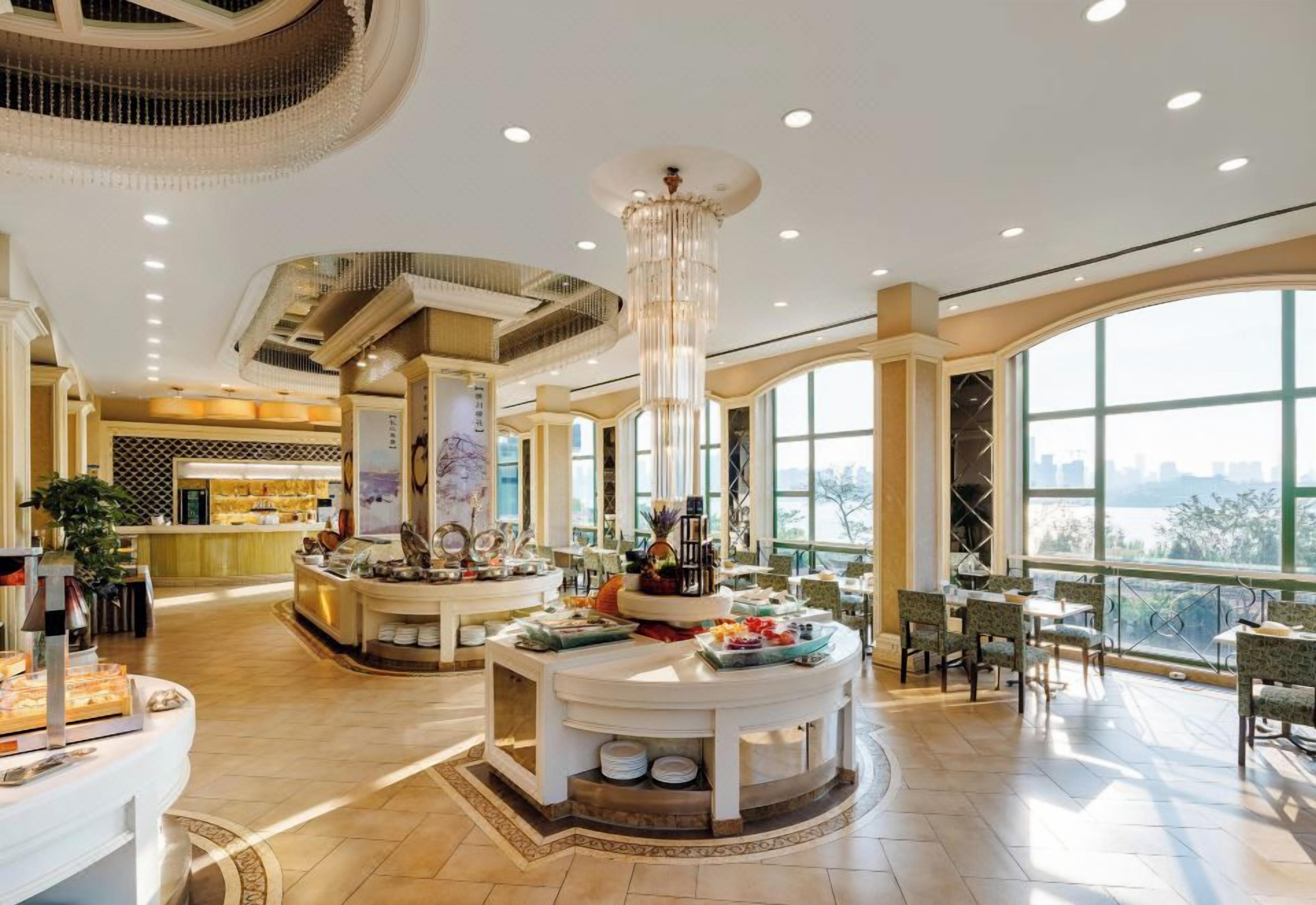 Un hall d’hôtel spacieux avec une grande table ronde au centre, un comptoir d’accueil et de larges fenêtres offrant une vue panoramique.
