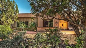 A single-story house with a front porch, surrounded by various plants and trees. - Myrinn – Private Hot Tub & Red Rock Views (Sedona)