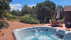 A hot tub with multiple jets, surrounded by a patio area with outdoor furniture and a barbecue grill. - Myrinn – Private Hot Tub & Red Rock Views (Sedona)