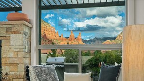 A patio with a stone wall, a grill, and a view of red rock formations. - Myrinn – Red Rocks Views & Cathedral Rock Trail (Sedona)