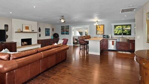 Amplia sala de estar con sofá de cuero, chimenea y cocina con una isla grande.