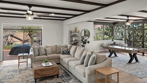 Amplia sala de estar con un sofá seccional grande, una mesa de centro y una mesa de billar.