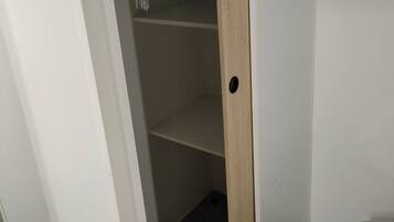 A room with a wooden door leading to a closet with shelves.