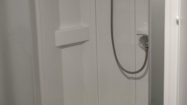 A white shower enclosure with a handheld showerhead and a fixed showerhead. - 8-person mobile home, ideal for families! Sheets & towels included (Condrieu)