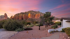 A desert landscape with rock formations, a house, and a garden.