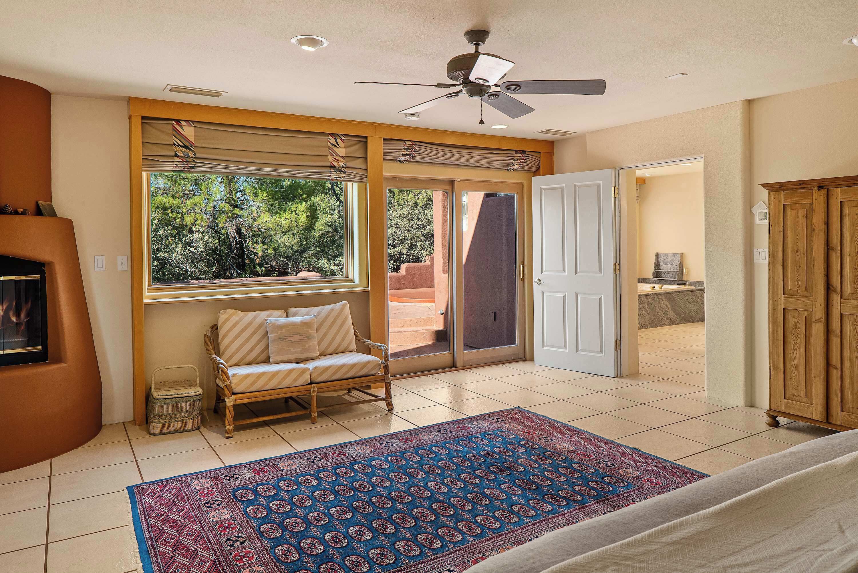 A living room with a sofa, a patterned rug, a ceiling fan, and a view of the outdoors.