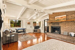 Un salon spacieux doté d’une cheminée, de parquet et d’un ventilateur de plafond.