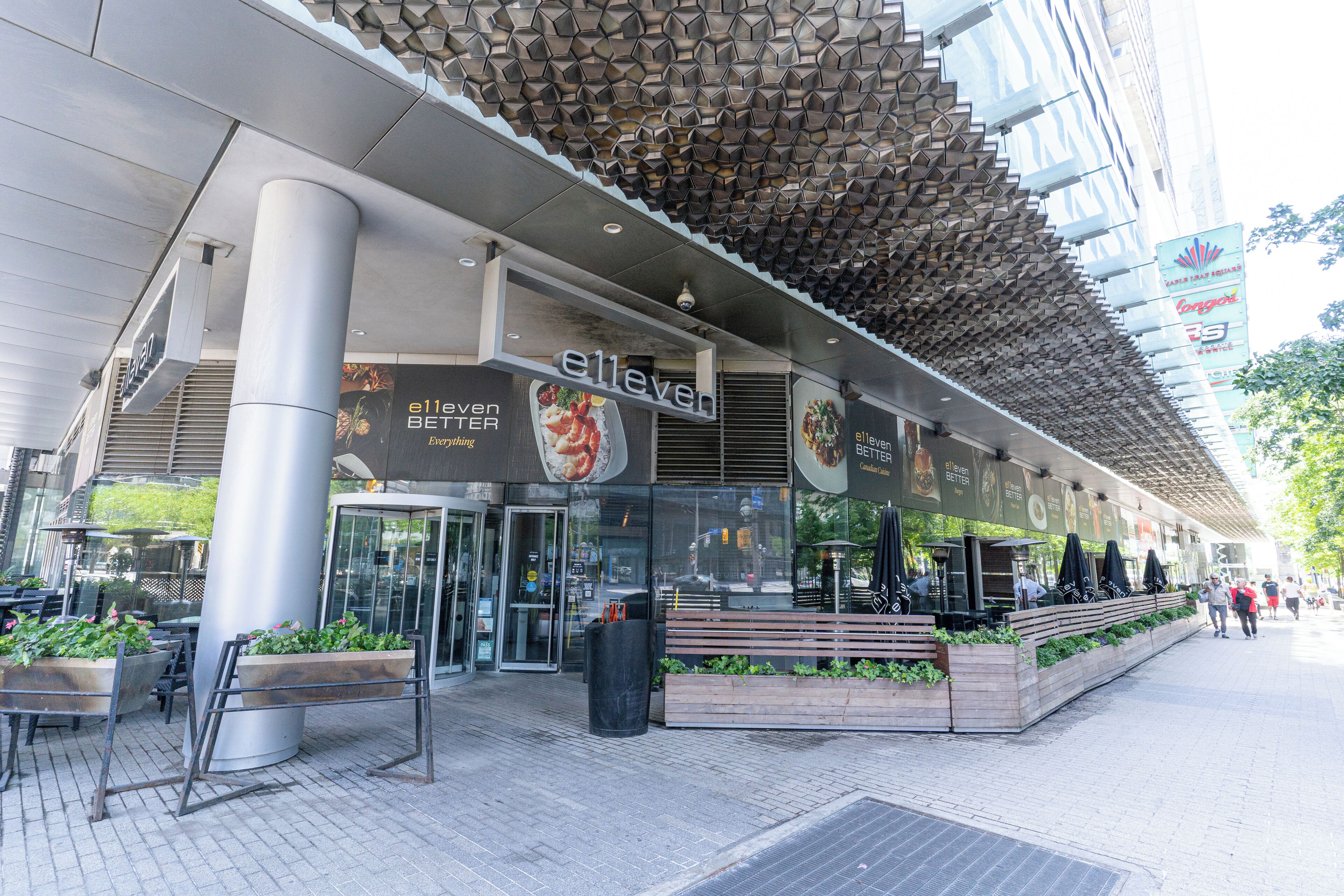 A modern building with a distinctive geometric ceiling, large glass windows, and outdoor seating areas.
