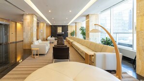 Un hall d’hôtel moderne avec un long canapé, une table ronde et un comptoir d’accueil en arrière-plan.