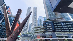 Un paysage urbain moderne, avec de hauts immeubles, une sculpture remarquable et un ciel dégagé.