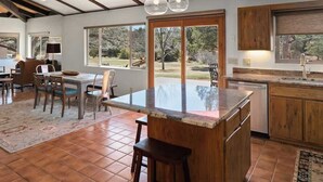 Una cocina amplia con una isla grande, armarios de madera y un comedor con mesa y sillas.