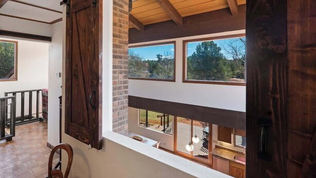 Una habitación con un ventanal grande, vigas de madera en el techo y vistas al exterior.