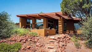 Ein modernes Haus mit einer Terrasse, großen Fenstern und einem Steinfundament.