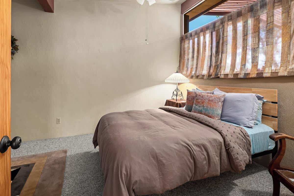 A bedroom with a bed, a nightstand, a lamp, and a window with curtains.