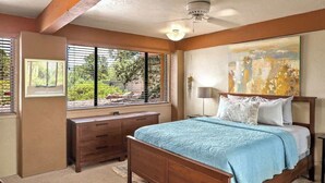 Ein Schlafzimmer mit einem hölzernen Bett, einem Nachttisch, einer Kommode und einem großen Fenster mit Jalousien.