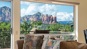 Ein Zimmer mit einem großen Fenster, das Blick auf rote Felsformationen und einen Turm bietet.
