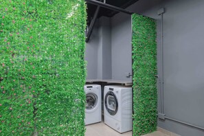 Convenient laundry facilities with two washing machines, surrounded by lush foliage.