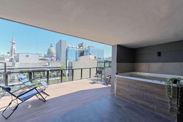 Relax on the balcony with unobstructed city views, a bench, and a potted plant.