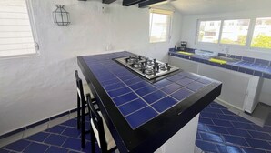 A kitchen with a blue-tiled island, a gas stove, and a window. - OCEAN VIEW PENTHOUSE WITH TERRACE (Manzanillo)