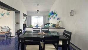 A dining area with a glass table, black chairs, and a ceiling fan. - OCEAN VIEW PENTHOUSE WITH TERRACE (Manzanillo)