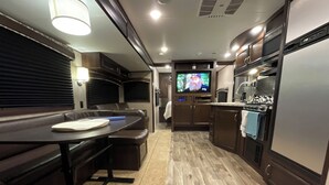 Une cuisine compacte pour camping-car, comprenant un coin repas, un téléviseur et une cuisinière.