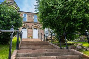 A set of stone steps leading to a building with arched windows and a white door. - Hillside Luxury Apartments (Inverness)