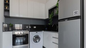 A modern kitchen with stainless steel appliances, including a washing machine, oven, and refrigerator. - MOT Rentals + GuateFlat 'G' 2 Bd in Palermo Soho (Buenos Aires)