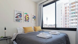 A modern hotel room with a large bed, two pillows, a nightstand with a lamp, and artwork on the wall. - MOT Rentals + GuateFlat 'G' 2 Bd in Palermo Soho (Buenos Aires)