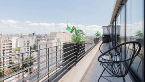 A balcony with a view of a cityscape, featuring a railing, a table with chairs, and potted plants. - MOT Rentals + GuateFlat 'G' 2 Bd in Palermo Soho (Buenos Aires)