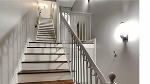 A staircase with wooden steps and white railings, leading to an upper floor. - Charming 2-bedroom condo located on the Historic Strand with WiFi, AC (Galveston)