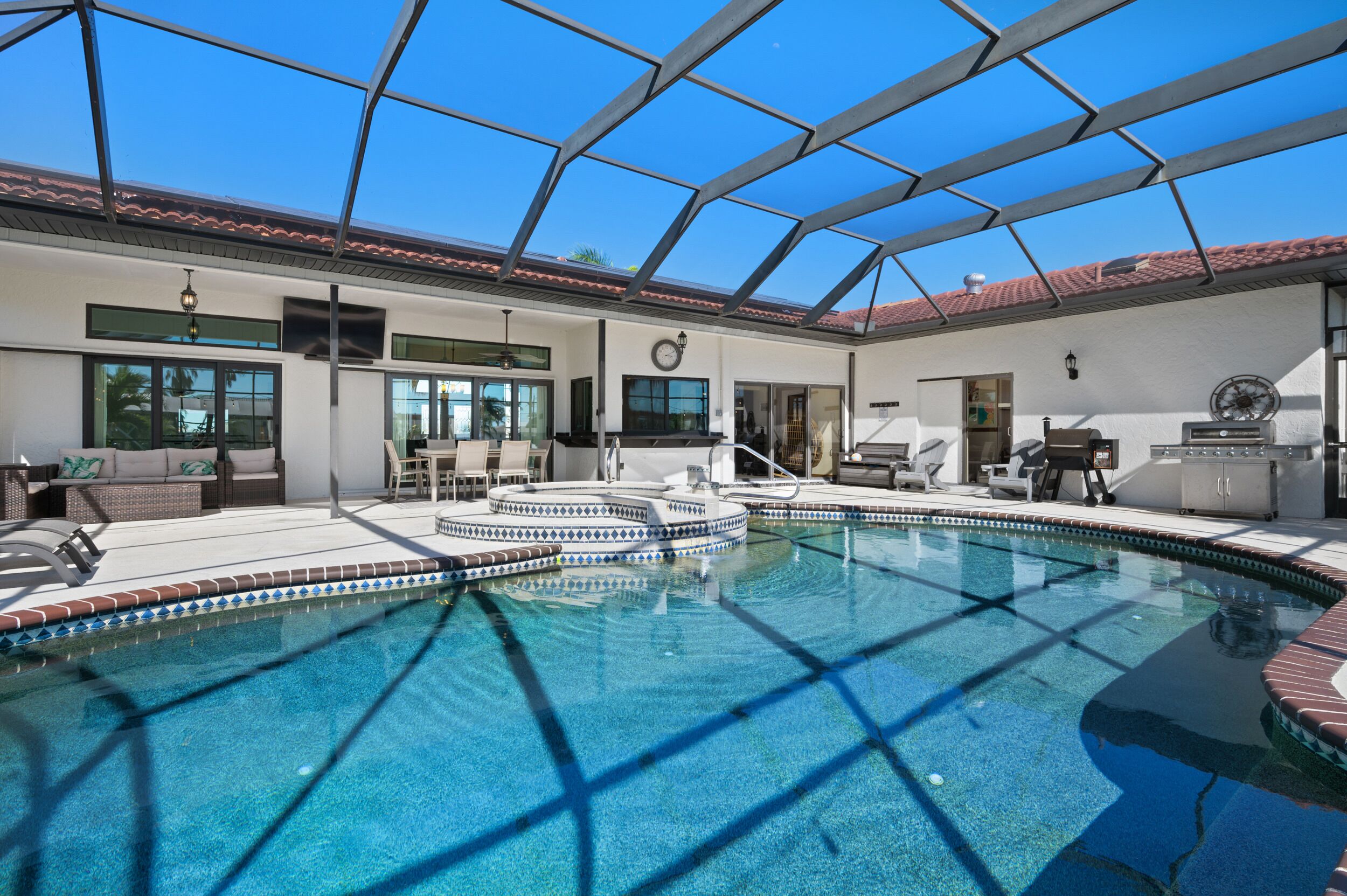A pool area with a glass ceiling, a sun terrace, and a dining area with outdoor furniture.