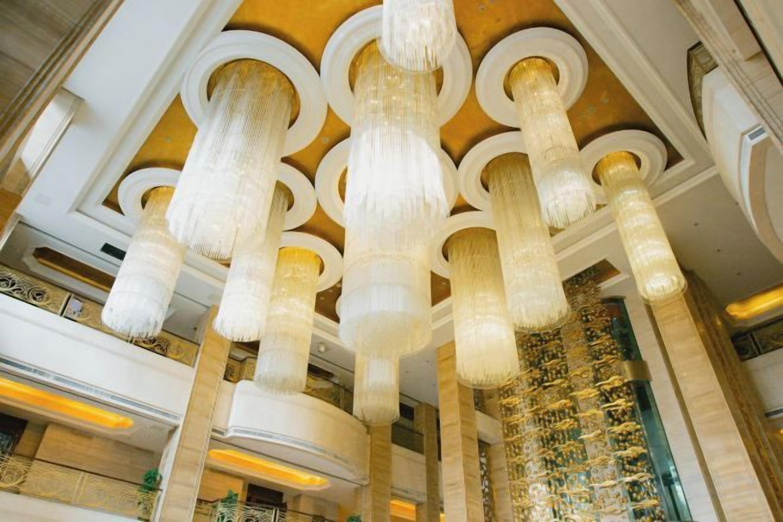 A grand interior with ornate chandeliers, high ceilings, and classical architecture.