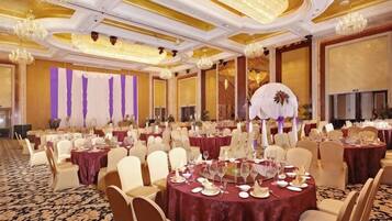 A banquet hall with round tables, chairs, and a chandelier.