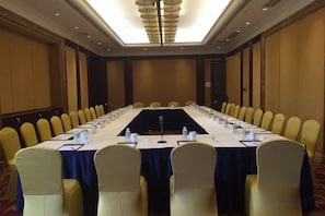 Un salón de conferencias con una larga mesa, sillas y un micrófono.