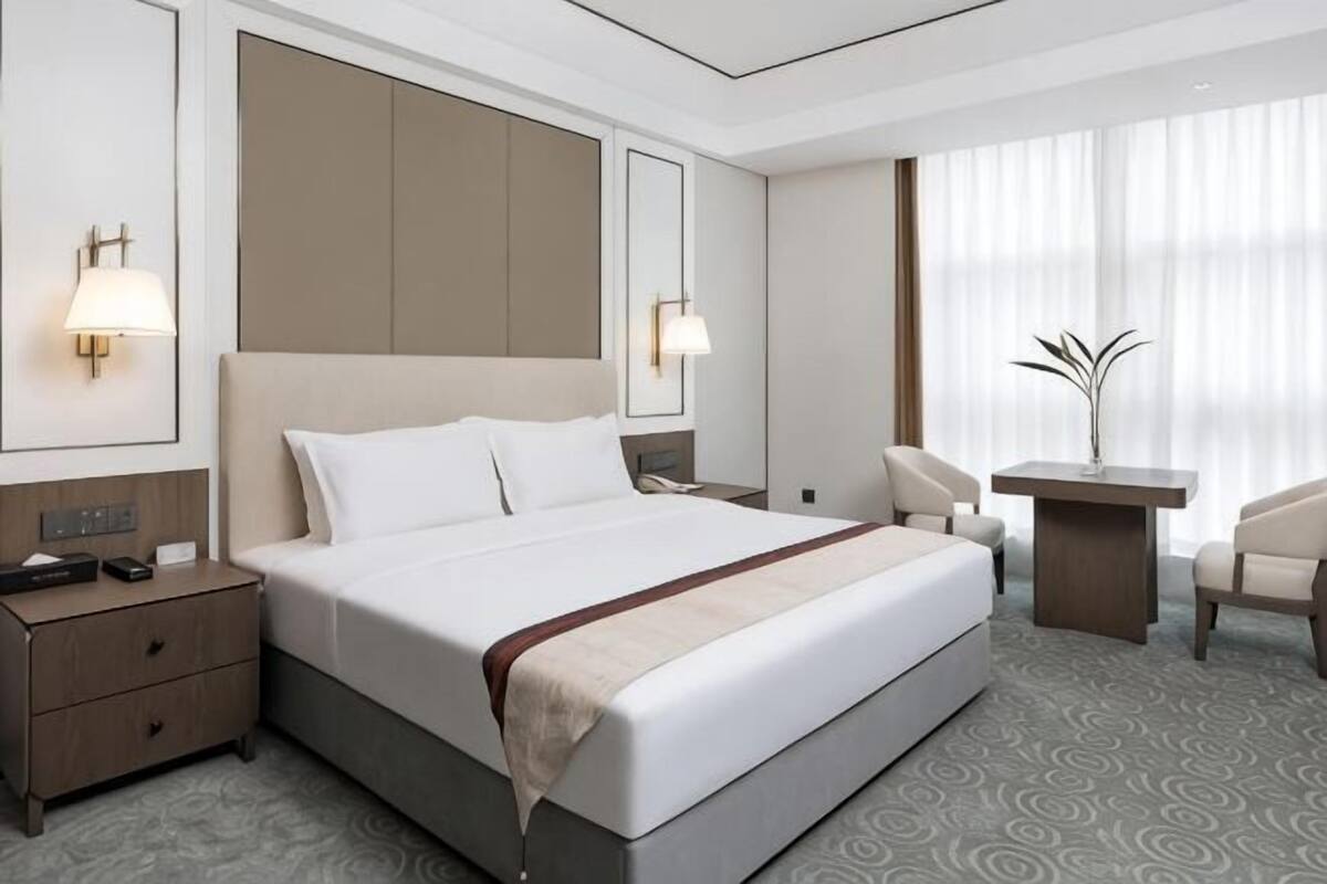 A hotel room with a large bed, bedside tables, a desk, and a chair.