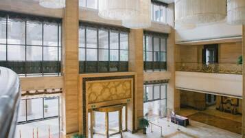 A spacious lobby with high ceilings, large windows, and a grand staircase.