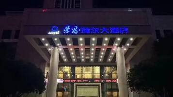 A hotel entrance with illuminated signage and a covered entrance area.