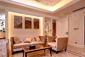 A well-lit living room with a sofa, armchair, and coffee table. - Rui'er Hotel (Chongqing)