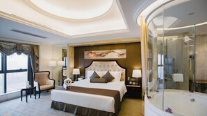 A hotel room with a large bed, a glass-enclosed shower, a desk with a chair, and a view of the city. - Rui'er Hotel (Chongqing)