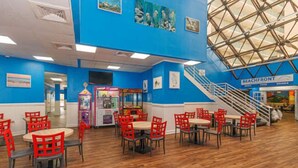 Un restaurant aux murs bleus, au plancher en bois, aux chaises rouges et doté d’un escalier menant à un balcon.