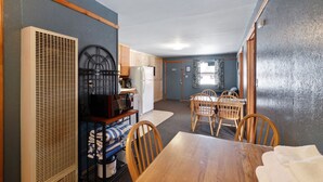 Une cuisine compacte équipée d’un réfrigérateur, d’une cuisinière et de meubles de rangement en bois. On y trouve également un coin repas avec une table et des chaises en bois.